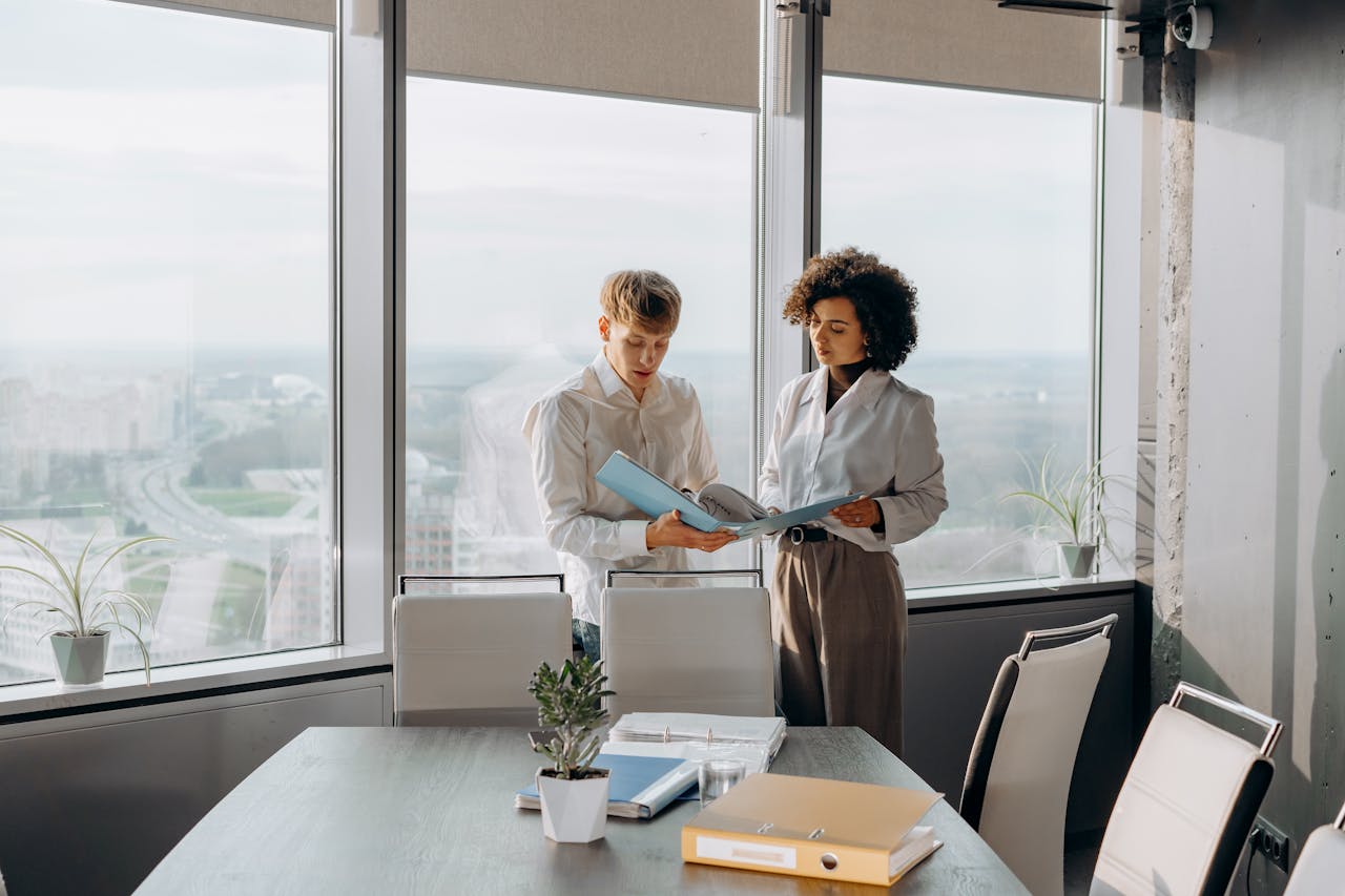 Two business professionals discussing paperwork in a bright, modern office setting.